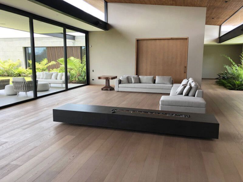 Amplio salón con ventanal y tarima de madera en tono roble