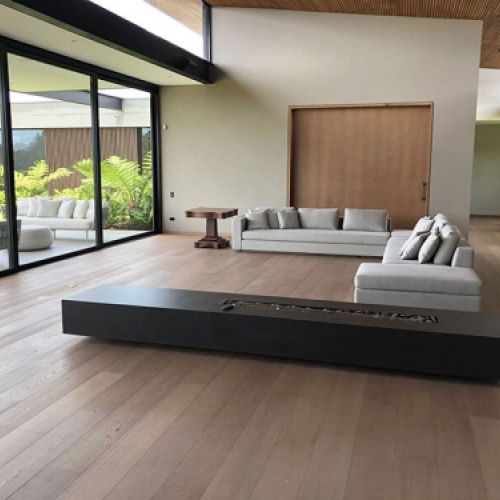 Amplio salón con ventanal y tarima de madera en tono roble